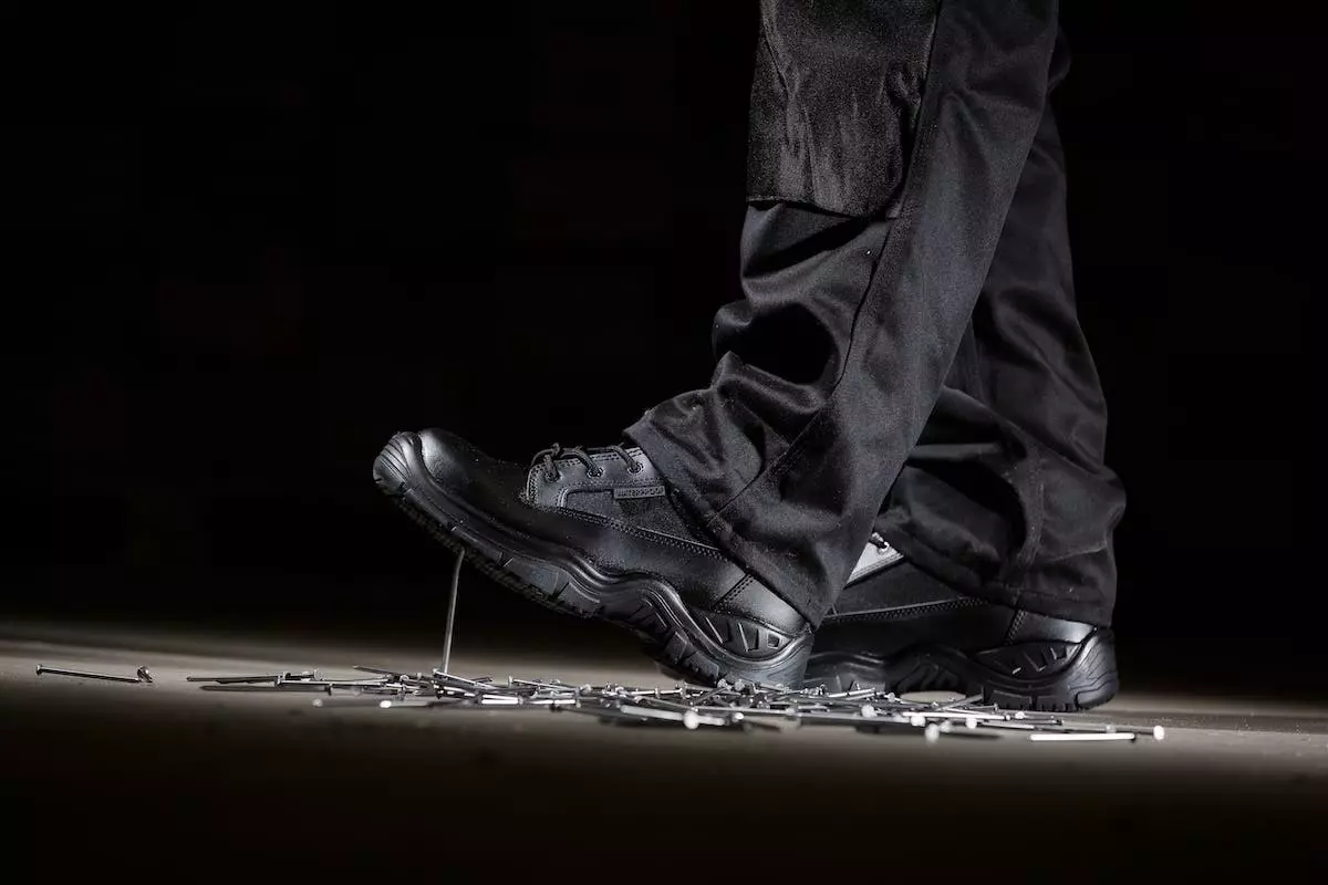 Someone wearing safety boots standing on a pile of nails